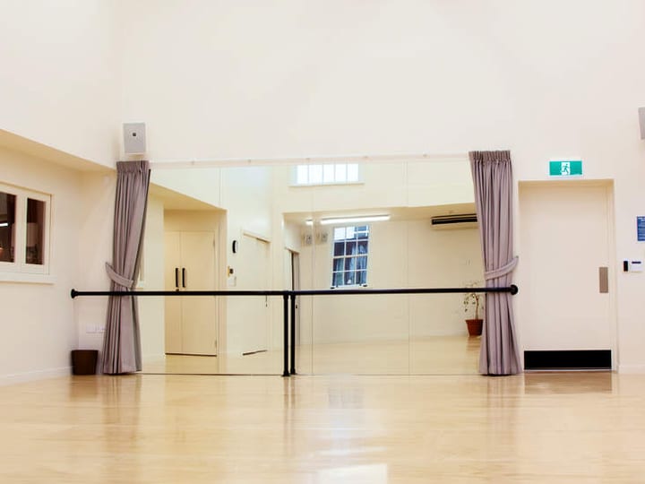 Dance studio with mirrored wall, ballet barre and timber sprung floor