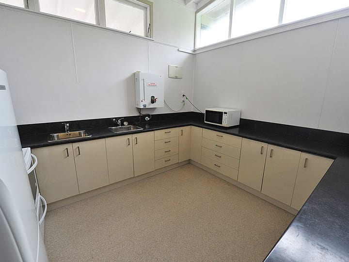 Plain white hall with dark timber-panelled wainscotting, polished floor, and fluorescent lighting