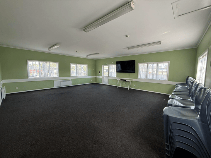 Plain hall with dark carpet, green walls, and wall-mounted TV