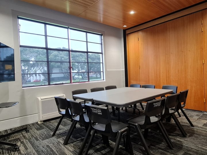 Small empty room with tall windows and folding timber partition