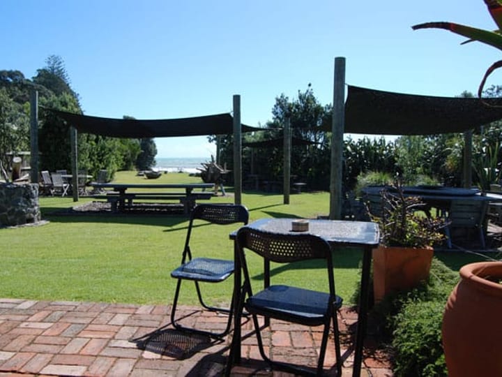 Grassed outdoor event area with shade sails and outdoor furniture, ocean views beyond