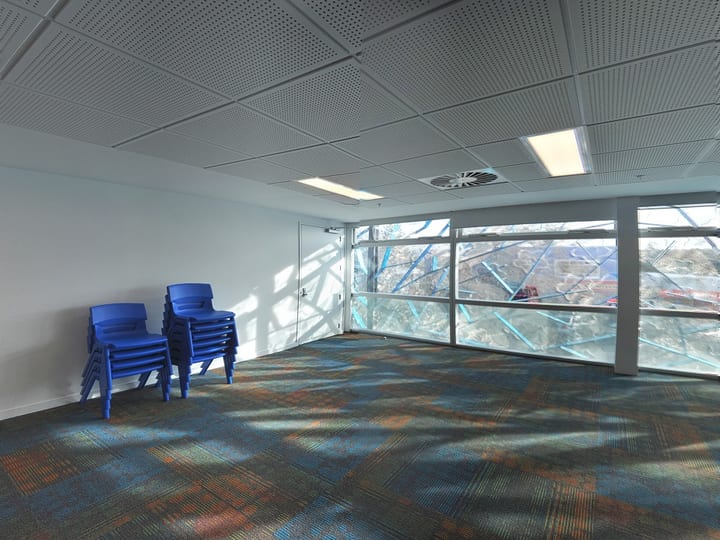 Empty room with blue stacked chairs and large glazed windows