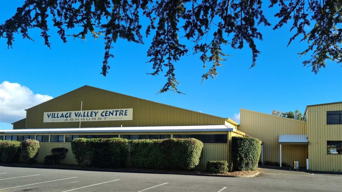 Village Valley Centre Ashhurst, a large yellow-clad building with hedges and a car park