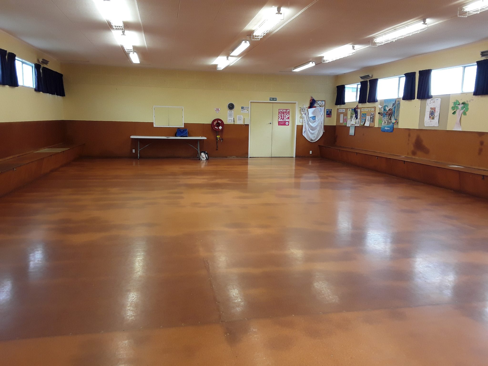 Plain rectangular hall with brown lino floor and fluorescent lighting