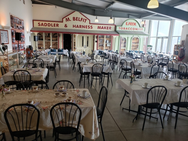 Museum hall set with tables and chairs in front of old shopfront displays