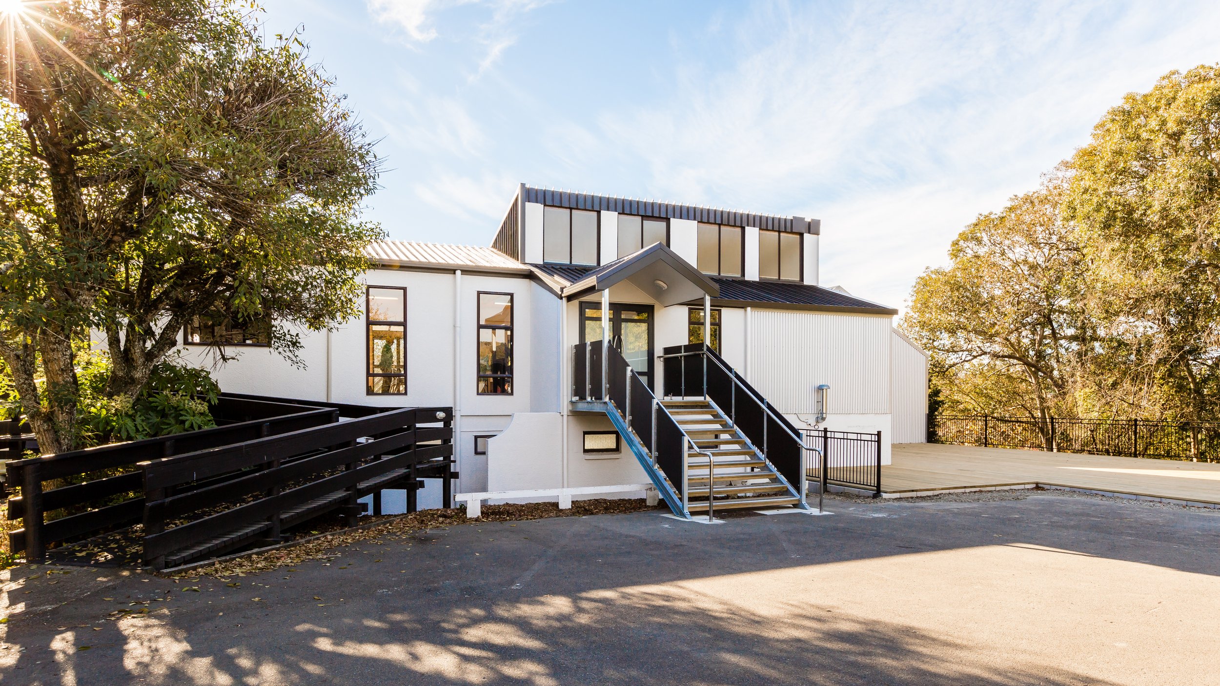 White building with a black external staircase, ramp and sealed car park