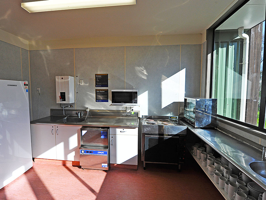 Commercial kitchen with stainless benches, dishwasher and crockery