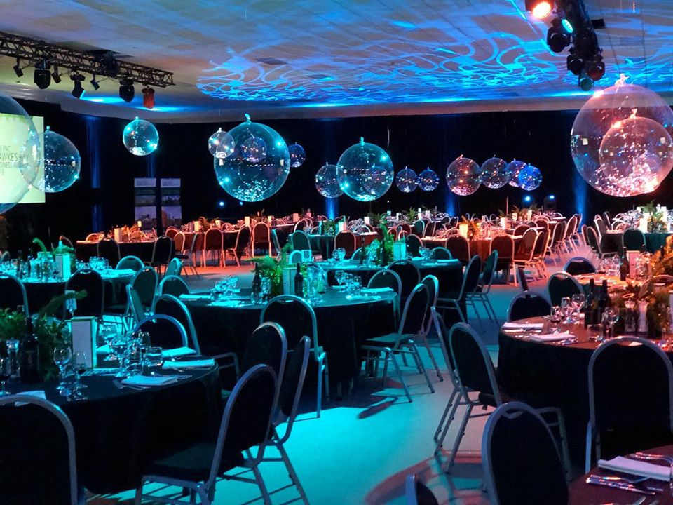 Large function room set with round tables, hanging clear spheres and coloured lighting