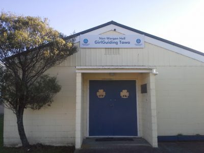 Small block-construction hall with blue doors and signage above entry