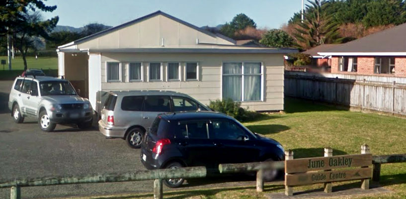 Single-storey hall building with cars parked in front and entry sign