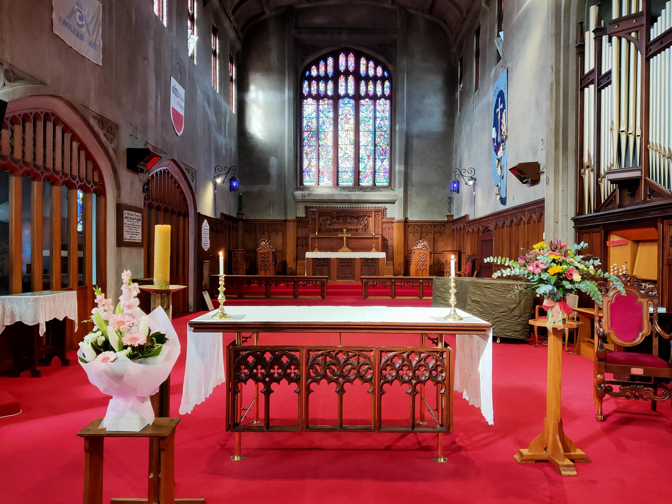 Church interior with stained glass window, altar table, red carpet and organ pipes