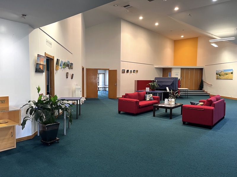 Large open room with teal carpet, red sofas and artwork on the walls