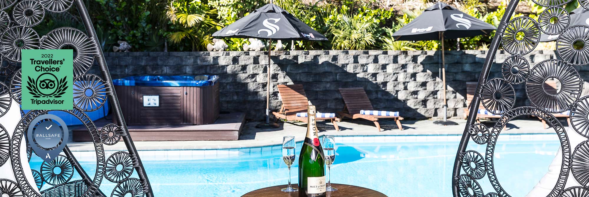Outdoor pool area with sun loungers and hot tub surrounded by stone wall