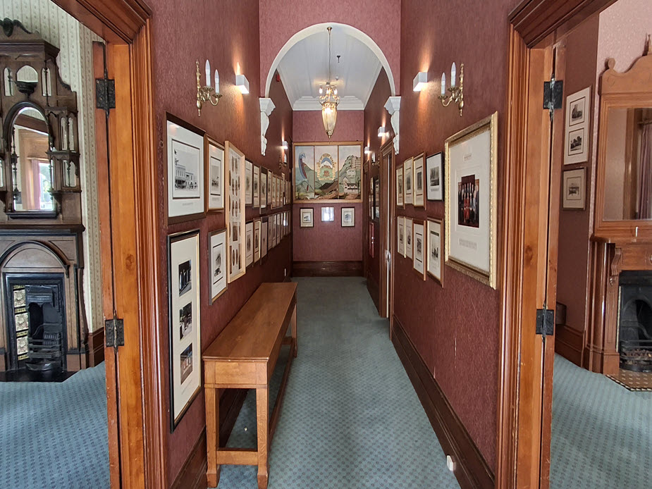 Hallway lined with framed photos and artwork, arched alcove and bench seat