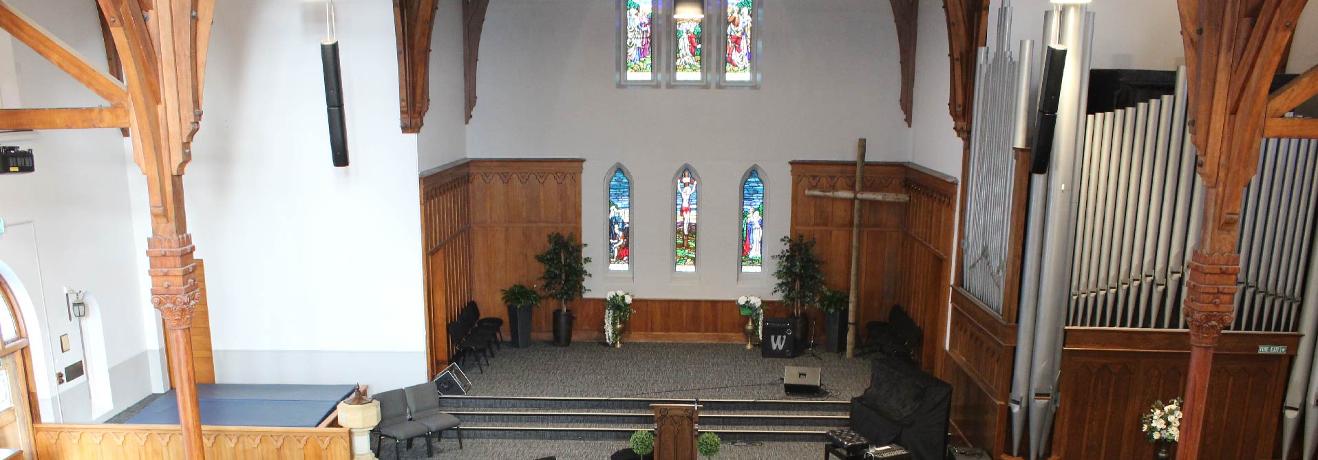 Church sanctuary from balcony showing stained glass, organ pipes and raised platform