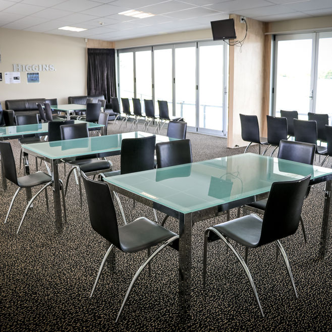 Function room with glass-topped tables, black chairs and large folding glass doors