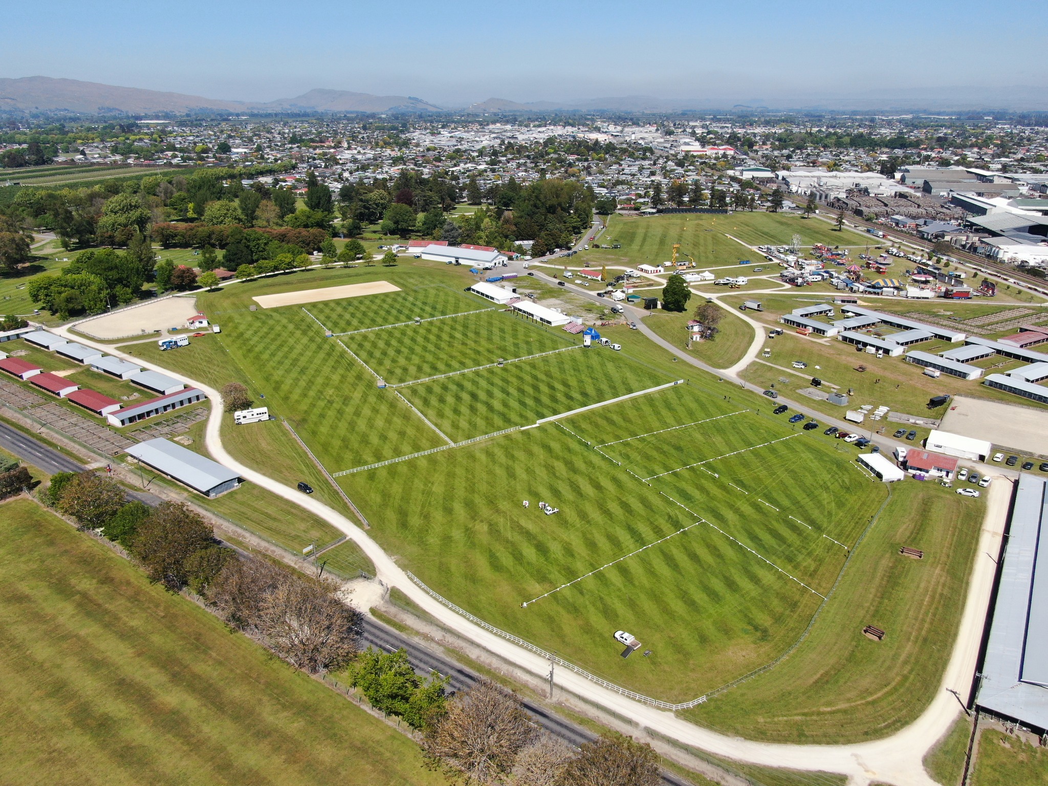 Aerial view of mown showgrounds with paths, sheds and surrounding town
